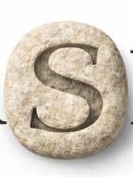 The ASHMN stone mark — hand-carved S in travertine